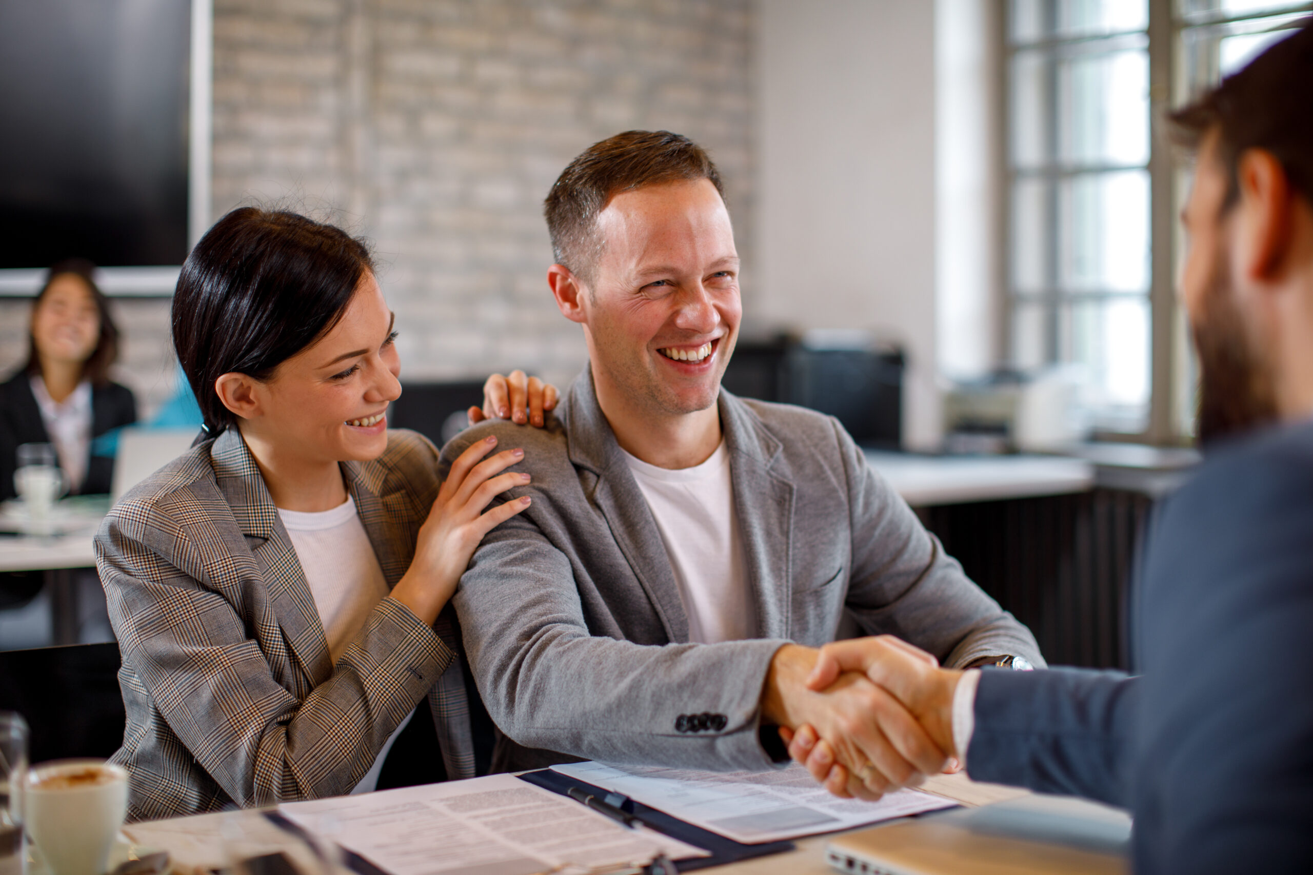 Happy young couple make a deal with their personal financial advisor in bank